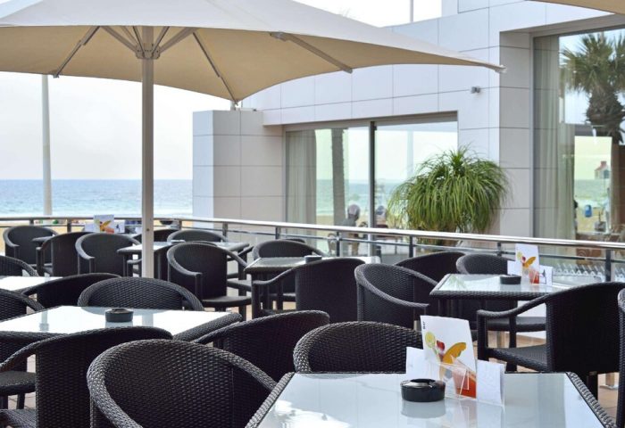 Sol Costablanca Adults-only Hotel: Outdoor terrace with tables, chairs, and ocean view. Gay-friendly hotel in Spain.