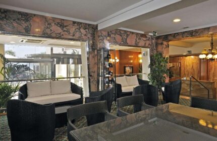 Sol Costablanca Adults-only hotel lobby. Seating area with rattan furniture, marble walls, and a view of the entrance. Gay-friendly hotel.