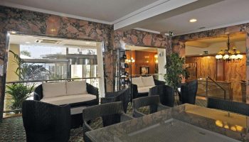 Sol Costablanca Adults-only hotel lobby. Seating area with rattan furniture, marble walls, and a view of the entrance. Gay-friendly hotel.
