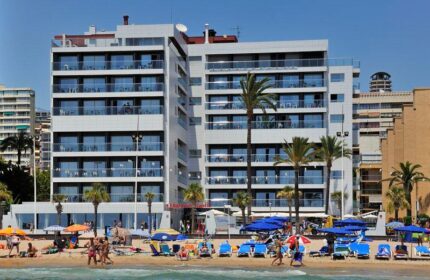 Sol Costablanca Adults-only hotel. Gay-friendly hotel on the beach. People enjoy the beach in front of the hotel. Palm trees.