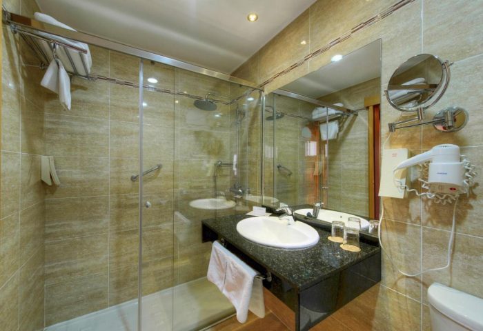 Sol Torremolinos Don Pablo gay-friendly hotel bathroom. Shower with glass door, sink with granite countertop, mirror, and hairdryer.