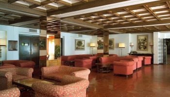 Lobby at Sol Torremolinos Don Pedro, a gay-friendly hotel. Seating area with sofas, chairs, and tables. Coffered ceiling and tile floor.