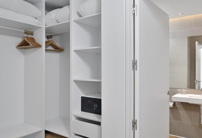 Sol Torremolinos Don Pedro gay-friendly hotel room closet. Open wardrobe with hangers, shelves, safe, and bathroom view.