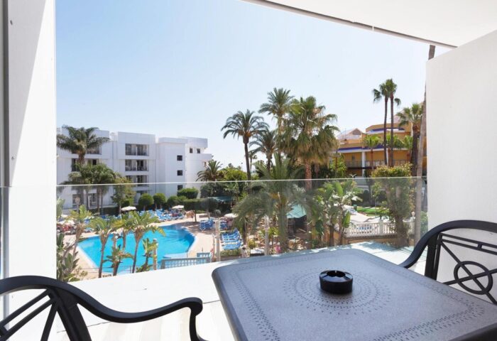 Balcony view at Sol Torremolinos Don Pedro, a gay-friendly hotel. See the pool, palm trees, and sunny skies. Perfect for gay travel.