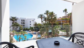 Balcony view at Sol Torremolinos Don Pedro, a gay-friendly hotel. See the pool, palm trees, and sunny skies. Perfect for gay travel.