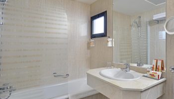 Bathroom at gay-friendly Sol Torremolinos - Don Pedro hotel. Bathtub, sink, mirror, and toiletries. Ideal for gay travel in Torremolinos.