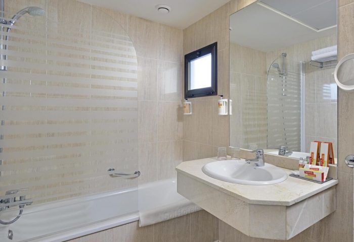 Bathroom at gay-friendly Sol Torremolinos - Don Pedro hotel. Bathtub, sink, mirror, and toiletries. Ideal for gay travel in Torremolinos.