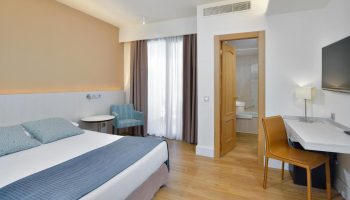 Sol Torremolinos Don Pedro hotel room. Gay-friendly hotel bedroom with double bed, desk, chair, and bathroom. Modern, clean design.