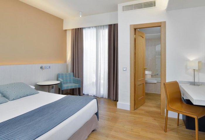 Sol Torremolinos Don Pedro hotel room. Gay-friendly hotel bedroom with double bed, desk, chair, and bathroom. Modern, clean design.
