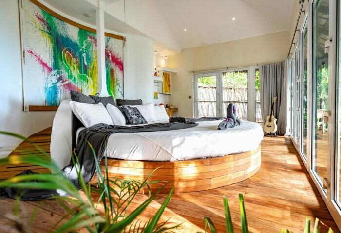 Gay-friendly hotel, Somewhere Only We Know: Round bed with swan towels, guitar, and colorful art. Luxury gay travel, romantic getaway.