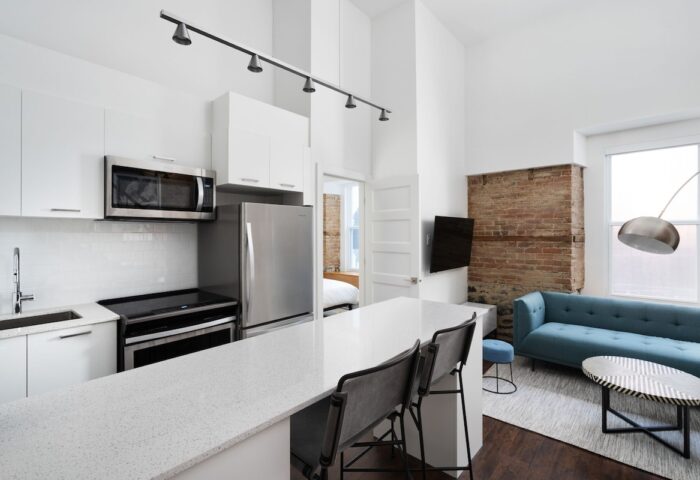 Sonder Gare Saint Denis gay-friendly hotel room. Modern kitchen, blue sofa, exposed brick. Stylish, comfortable stay for gay travelers.