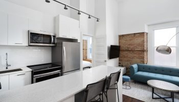 Sonder Gare Saint Denis gay-friendly hotel room. Modern kitchen, blue sofa, exposed brick. Stylish, comfortable stay for gay travelers.