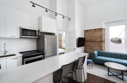 Sonder Gare Saint Denis gay-friendly hotel room. Modern kitchen, blue sofa, exposed brick. Stylish, comfortable stay for gay travelers.