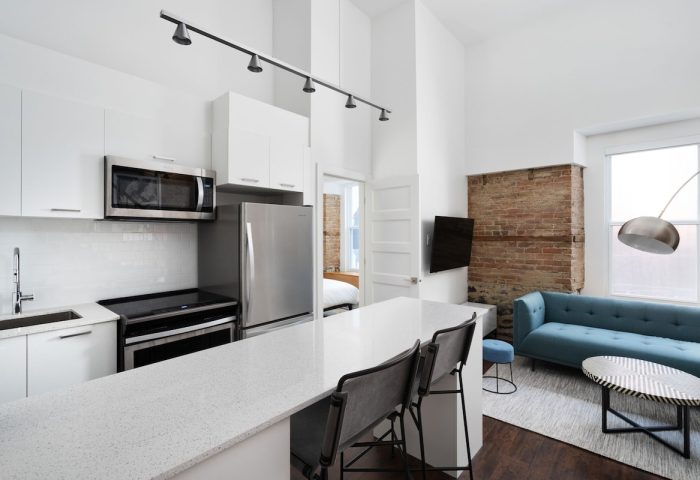 Sonder Gare Saint Denis gay-friendly hotel room. Modern kitchen, blue sofa, exposed brick. Stylish, comfortable stay for gay travelers.