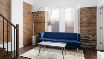 Sonder Gare Saint Denis gay-friendly hotel room. Blue sofa, brick wall, modern lamp. Stylish interior design for gay travelers.