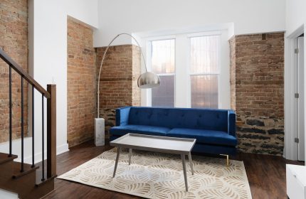 Sonder Gare Saint Denis gay-friendly hotel room. Blue sofa, brick wall, modern lamp. Stylish interior design for gay travelers.