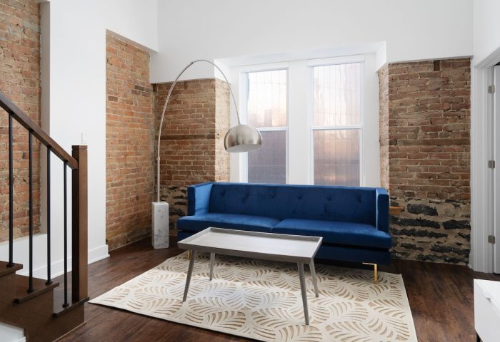 Sonder Gare Saint Denis gay-friendly hotel room. Blue sofa, brick wall, modern lamp. Stylish interior design for gay travelers.