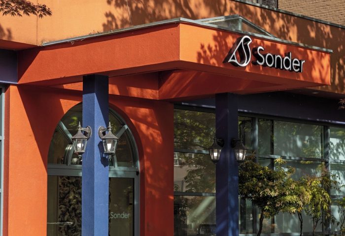 Sonder The Sunset, a gay-friendly hotel. The entrance boasts vibrant orange & blue colors, plants, and the Sonder logo for gay travelers.