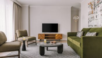 Gay-friendly Hotel Sonder The Sunset living space. Modern design with green sofa, chairs, TV, and stylish decor. Ideal for gay travelers.