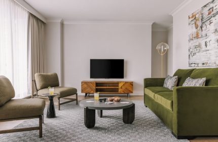 Gay-friendly Hotel Sonder The Sunset living space. Modern design with green sofa, chairs, TV, and stylish decor. Ideal for gay travelers.