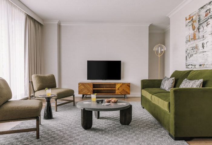 Gay-friendly Hotel Sonder The Sunset living space. Modern design with green sofa, chairs, TV, and stylish decor. Ideal for gay travelers.