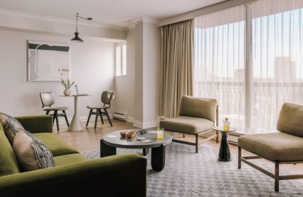 Sonder The Sunset gay-friendly hotel room. Modern interior with green sofa, chairs, table, and city view. Ideal for gay travel.