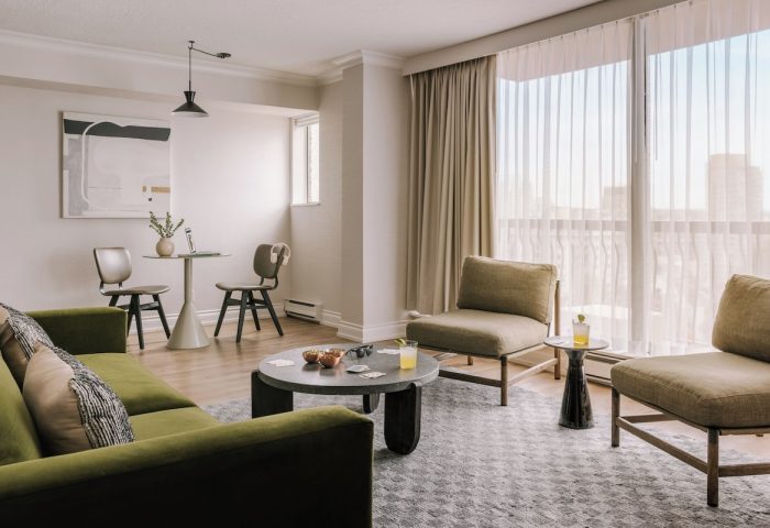 Sonder The Sunset gay-friendly hotel room. Modern interior with green sofa, chairs, table, and city view. Ideal for gay travel.