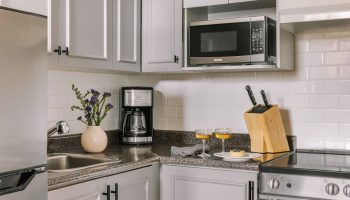 Sonder The Sunset's kitchen. Gay-friendly hotel with stainless fridge, microwave, coffee maker, stove, two drinks, and a knife block.