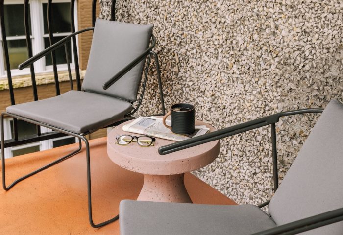 Sonder The Sunset hotel's gay-friendly patio. Two chairs flank a table with coffee, glasses, and a newspaper. Relaxing travel vibe.
