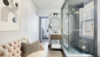 Sonder The Wellesley gay-friendly hotel bathroom. Glass shower, modern art, vanity, and glimpse of bedroom. Upscale design for gay travelers.