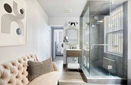 Sonder The Wellesley gay-friendly hotel bathroom. Glass shower, modern art, vanity, and glimpse of bedroom. Upscale design for gay travelers.