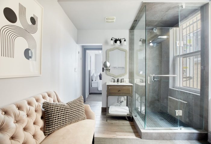 Sonder The Wellesley gay-friendly hotel bathroom. Glass shower, modern art, vanity, and glimpse of bedroom. Upscale design for gay travelers.
