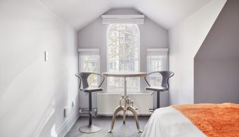 Sonder The Wellesley, a gay-friendly hotel. Room interior with table, stools, and bed. Ideal for gay travel advice and hotel stays.