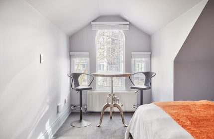Sonder The Wellesley, a gay-friendly hotel. Room interior with table, stools, and bed. Ideal for gay travel advice and hotel stays.
