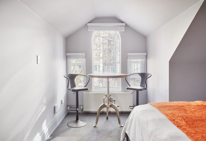 Sonder The Wellesley, a gay-friendly hotel. Room interior with table, stools, and bed. Ideal for gay travel advice and hotel stays.