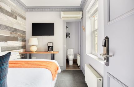 Sonder The Wellesley, gay-friendly hotel room. View of bed, TV, coffee maker, and bathroom. Modern design for gay men travelers.