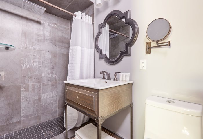 Sonder The Wellesley's bathroom. Gay-friendly hotel with shower, sink, and toilet. Mirror and decorative tile add style to this hotel bathroom.