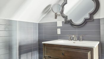 Sonder The Wellesley's bathroom. Gay-friendly hotel with a rustic vanity, ornate mirror, and gray tiles. A welcoming space for gay travelers.
