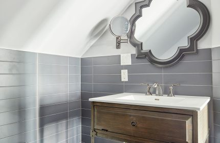 Sonder The Wellesley's bathroom. Gay-friendly hotel with a rustic vanity, ornate mirror, and gray tiles. A welcoming space for gay travelers.