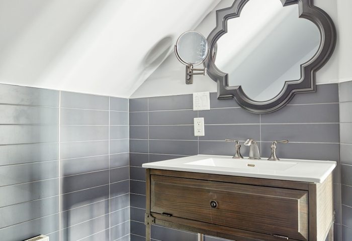 Sonder The Wellesley's bathroom. Gay-friendly hotel with a rustic vanity, ornate mirror, and gray tiles. A welcoming space for gay travelers.