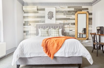 Sonder The Wellesley hotel room. Gay-friendly travel lodging with bed, orange throw, and decor. Modern design at this top gay travel destination.