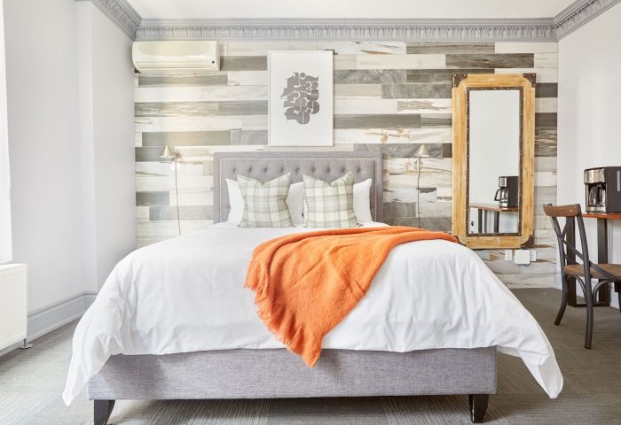 Sonder The Wellesley hotel room. Gay-friendly travel lodging with bed, orange throw, and decor. Modern design at this top gay travel destination.