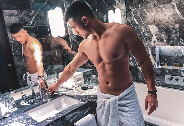 Gay-friendly South Place Hotel: Man in towel at bathroom sink. Pet-friendly hotel with luxury amenities for gay travel. Marble decor.