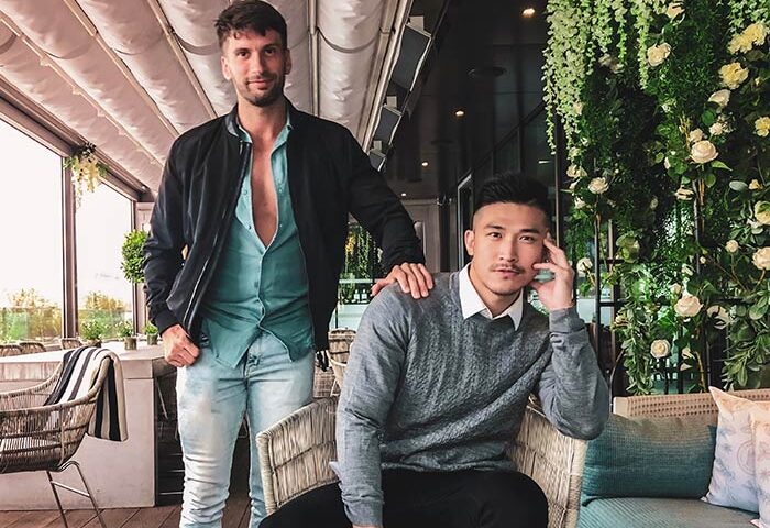 Two gay men at South Place Hotel. One stands with an open shirt and the other sits in a chair. Gay-friendly, pet-friendly hotel.