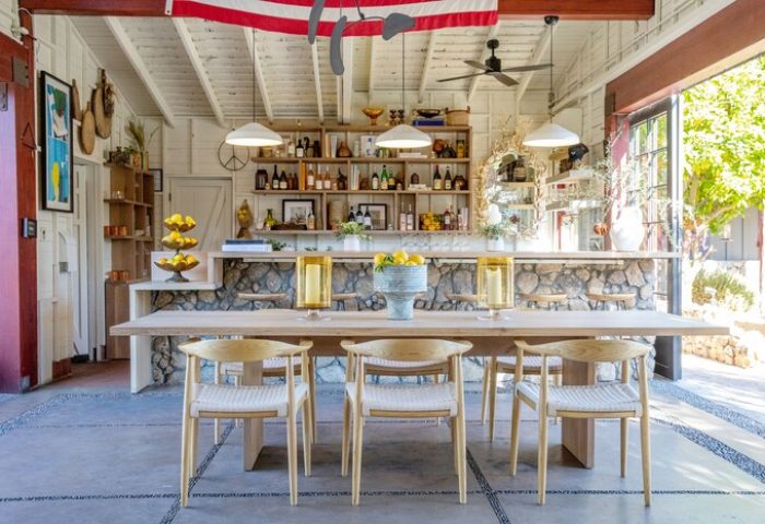 Sparrows Lodge, a gay-friendly hotel: Dining area with a long wooden table, chairs, stone bar, shelves with bottles, and an American flag.