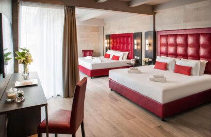 Spice Hotel Milano gay-friendly room. Red headboards, white linens, towels. Desk with flowers. Modern design, comfortable for gay travelers.