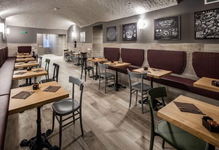 Spice Hotel Milano gay-friendly hotel restaurant. Tables and chairs line the room, with booth seating along one wall. Chalkboard art decorates.