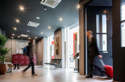 Spice Hotel Milano lobby. Gay-friendly hotel with modern design. Travelers arrive with luggage. Welcoming space for gay men's travel.
