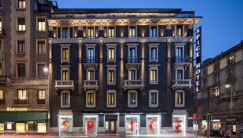 Exterior view of the gay-friendly Spice Hotel Milano at dusk. Facade with illuminated windows and Spice Hotel sign. Modern design in Milan.