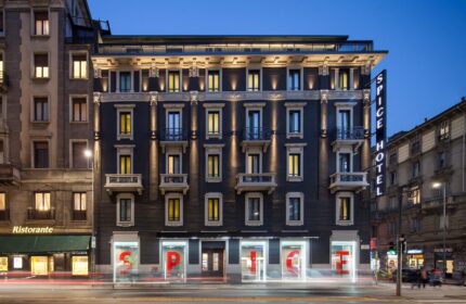 Exterior view of the gay-friendly Spice Hotel Milano at dusk. Facade with illuminated windows and Spice Hotel sign. Modern design in Milan.